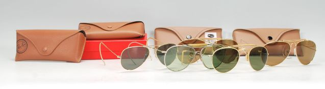 A group of vintage designer sunglasses to include two Ray Ban leather cases with one retaining