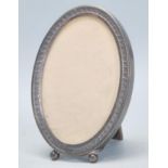 A early 20th Century silver mounted photo frame of oval form with engraved and repousse decoration