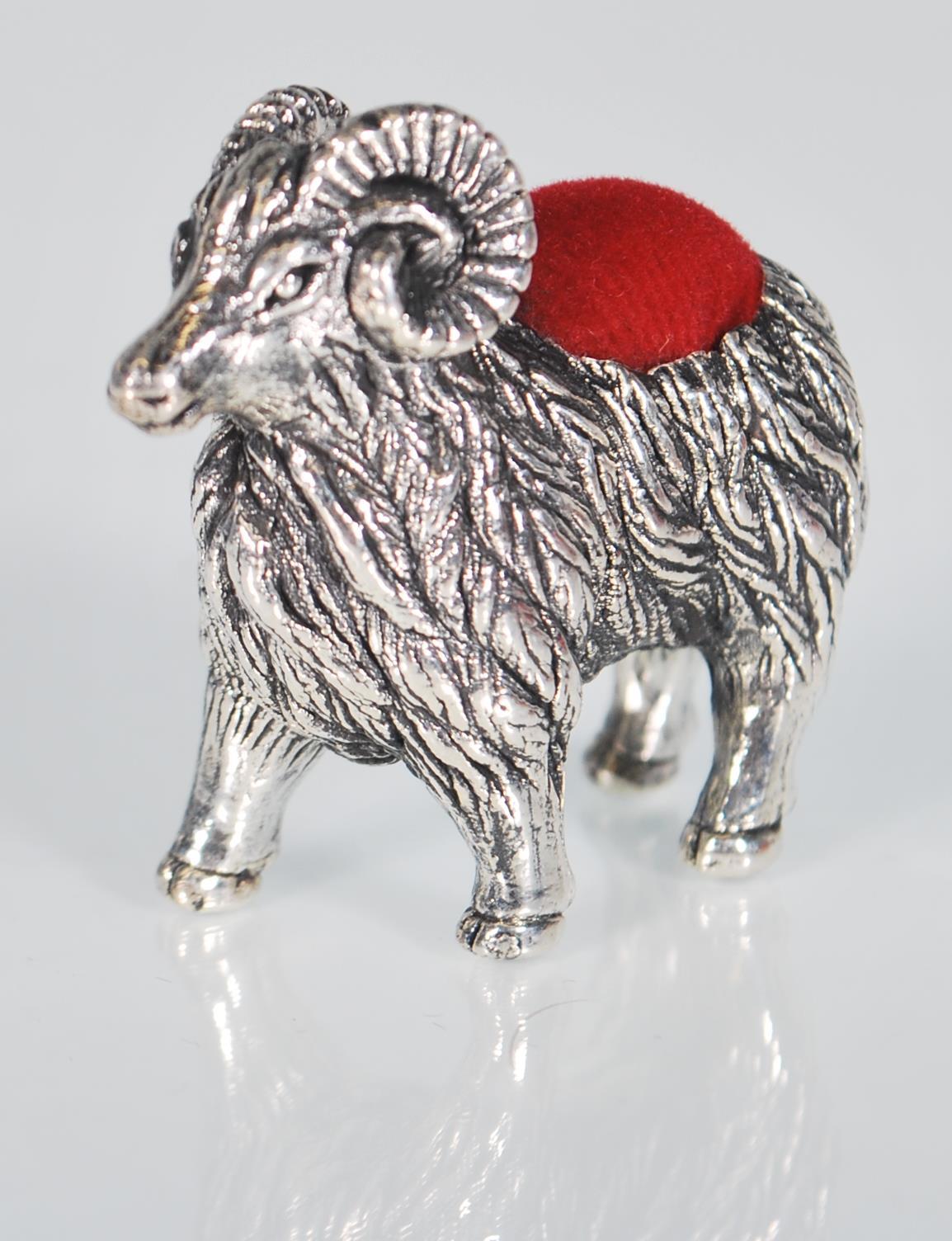 A small sterling silver pin cushion in the form of a ram. Measures: 3.4 x 4.3 x 1.2. Weight: 14.6g.