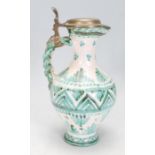 A 20th Century majolica jug of waisted form with a plaited design handle and pewter lid to the