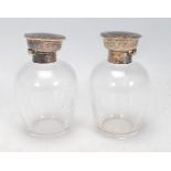 A pair of silver topped dressing table perfume bottles, each lid of round form set with tortoise