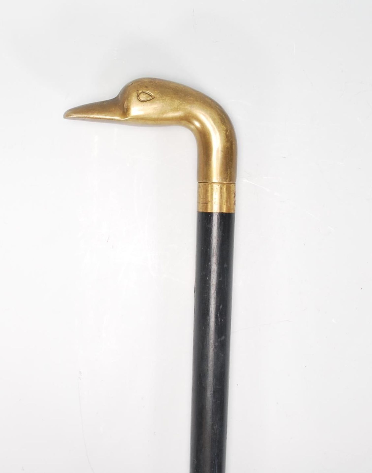 A vintage 20th Century walking stick cane having a tapering ebonise shaft with a cast brass handle