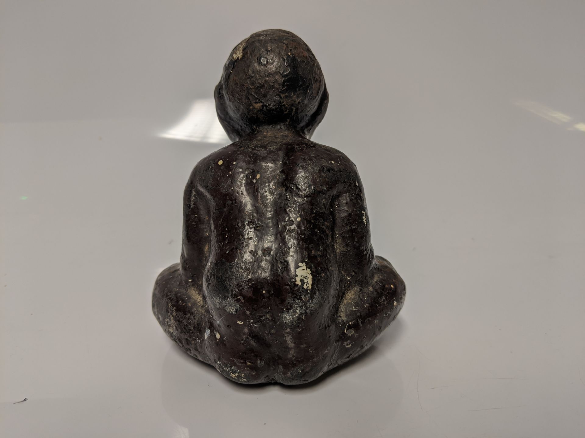 An early 20th century cast iron Black Americana paperweight / figurine of a seated male figure being - Bild 3 aus 5