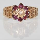 A hallmarked 9ct gold ring having a flower head set with round cut red stones and a central white