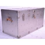 A large vintage metal covered travel trunk having brown leather carrying handles with blue lined