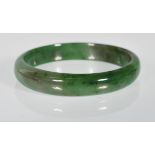 A Chinese green jade slave bangle of round plain form.