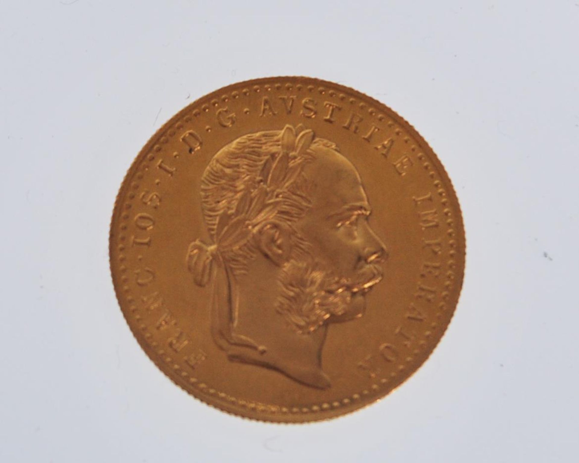 An 18ct gold Austrian 1 Ducat coin (restrike) having a head facing right and coat of arms to the
