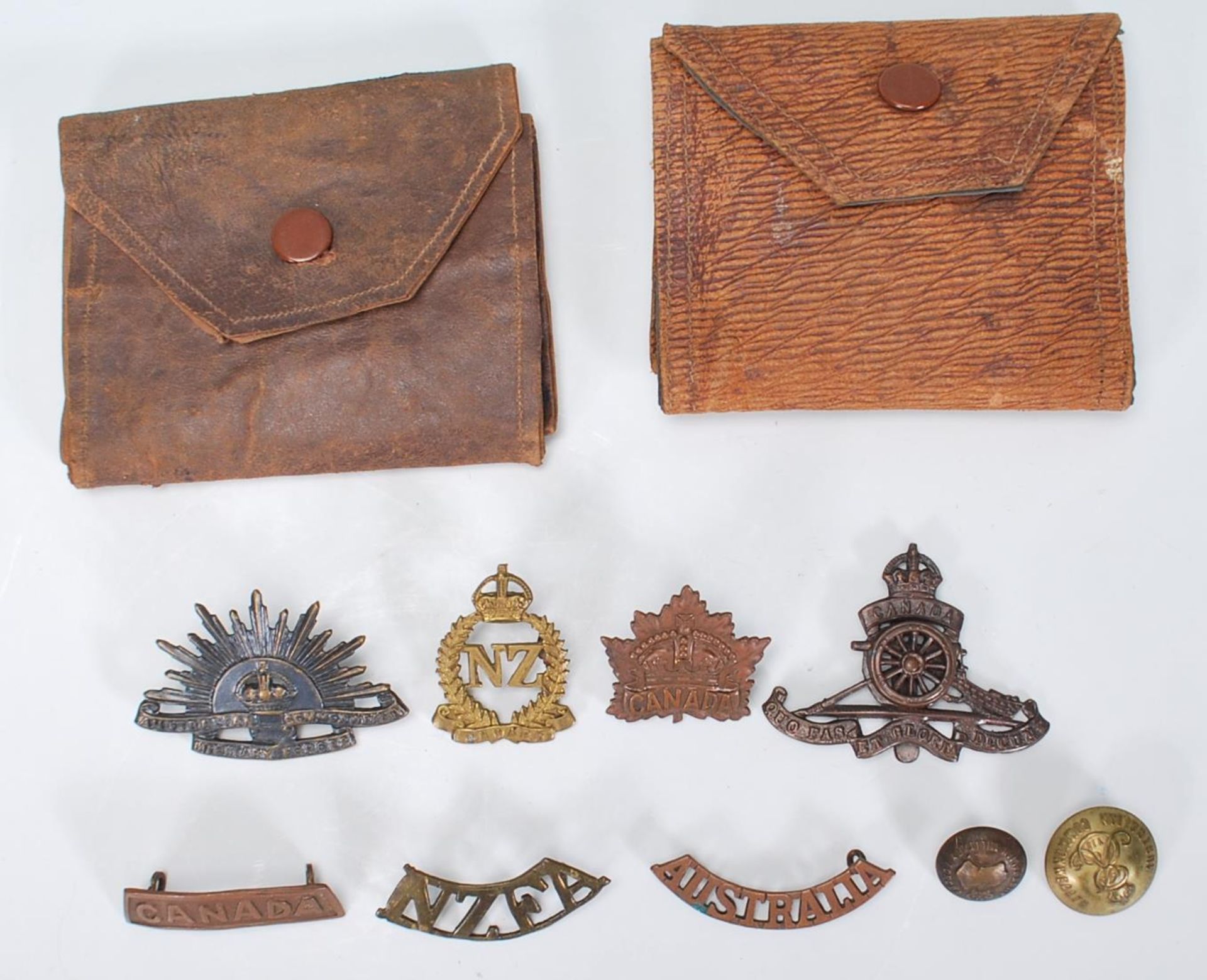 A small collection of circa World War One / WWI Commonwealth cap badges, name plates etc for