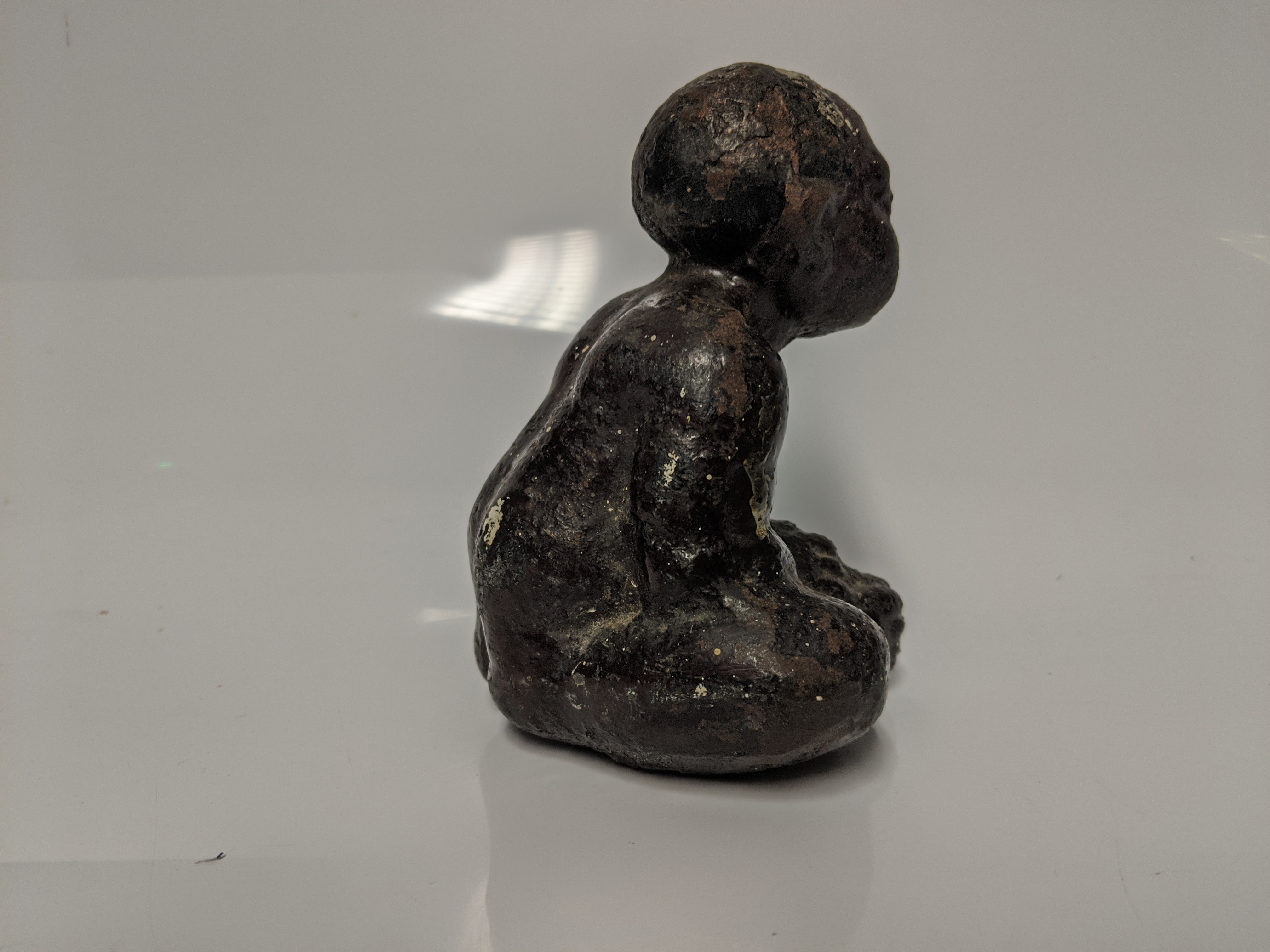 An early 20th century cast iron Black Americana paperweight / figurine of a seated male figure being - Image 5 of 5