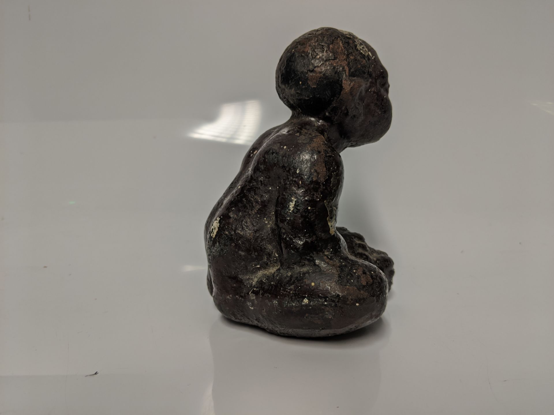 An early 20th century cast iron Black Americana paperweight / figurine of a seated male figure being - Bild 5 aus 5