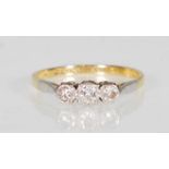 An 18k yellow gold and platinum mounted three stone diamond ring set with round cut diamonds of