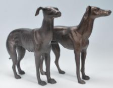 A pair of antique style cast iron sculpted figures of a male and female greyhound, each standing