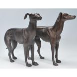 A pair of antique style cast iron sculpted figures of a male and female greyhound, each standing