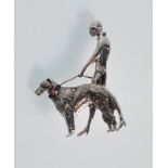 A figural sterling silver brooch depicting a figure walking a dog on a lead. The dogs collar is