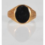 A hallmarked 9ct gold signet ring having an oval black stone panel set to the head with bark