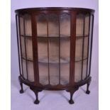 An early 20th Century Edwardian mahogany bow front / demi lune glass display cabinet being raised on