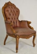 A 20th Century Antique style leather button back armchair raised on scroll supports with shaped