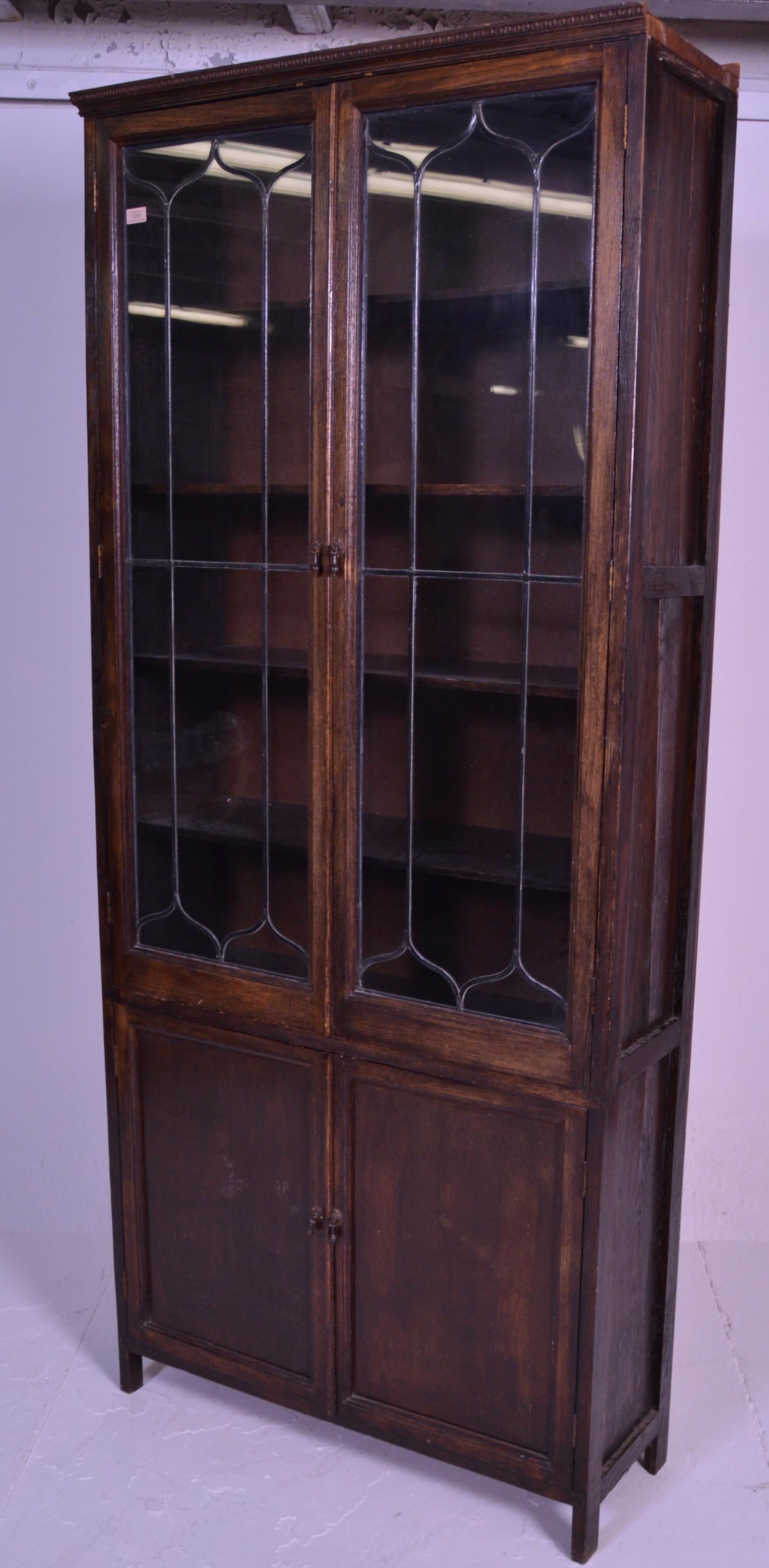 An early 20th Century 1920's oak bookcase having twin glazed lead lined glass doors over two oak