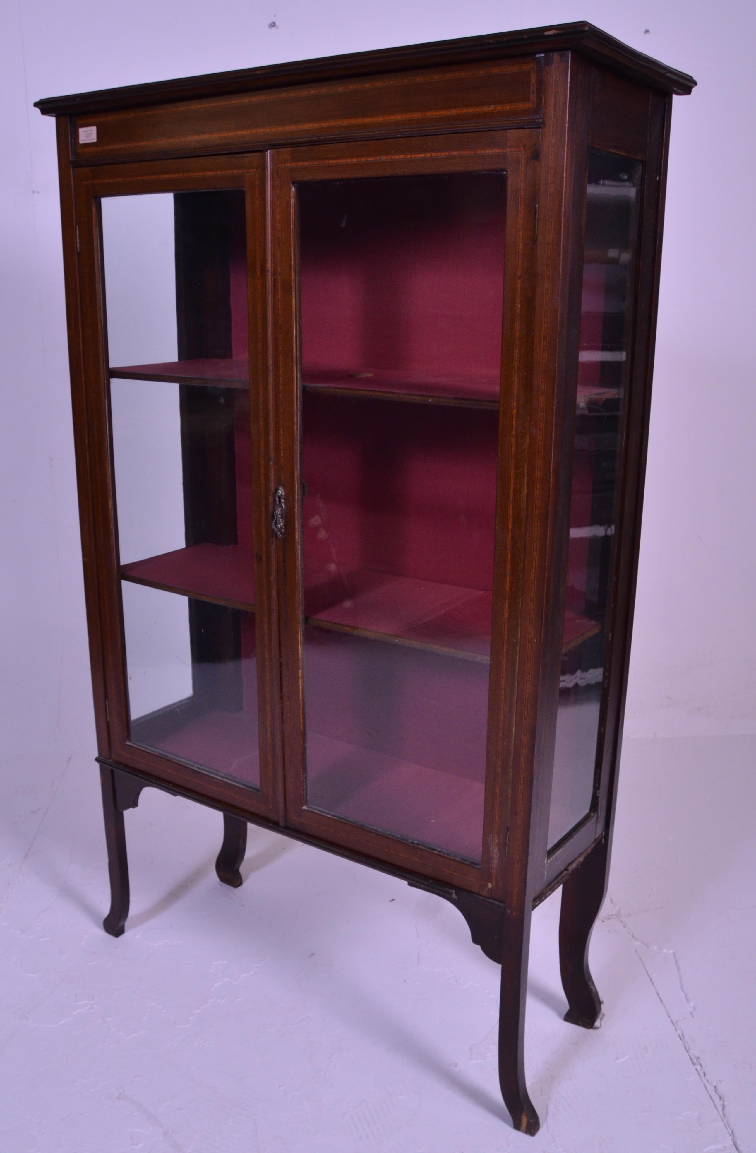 An early 20th Century inlaid mahogany display cabinet / bookcase raised on shaped supports with twin