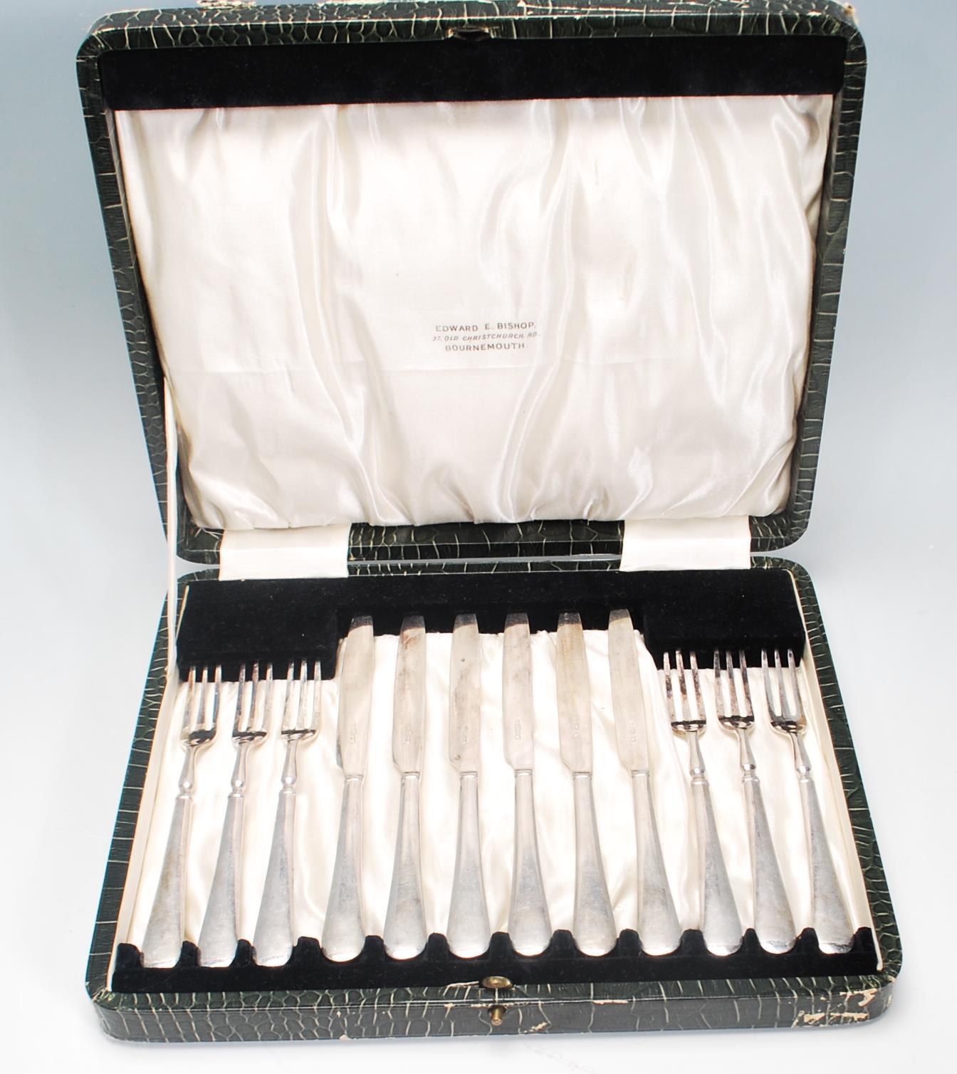 A vintage silver plated cake knife and fork set consisting of six knives and forks set within its