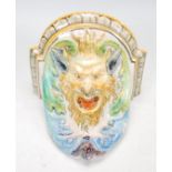 A 20th Century majolica wall bracket in the form of Bacchus modelled with scrolled acanthus leaves