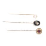 A group of three Victorian stick pins to include a pin set with a round cut amethyst in an engine