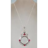 A ladies silver necklace with a silver magnifying glass pendant. Rubies and filigree work