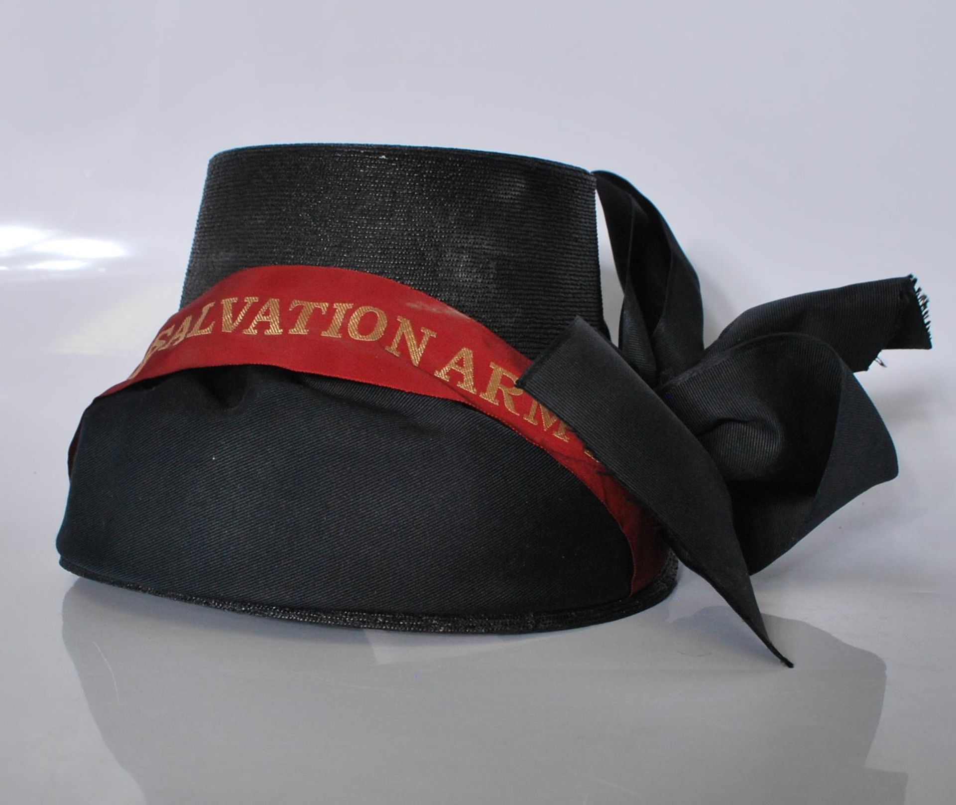 An early 20th Century Salvation Army bonnet finished in black having a red ribbon with gold