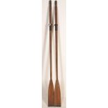 A large pair of early 20th Century decorative pine boat oars with metal banding and shaped ends.