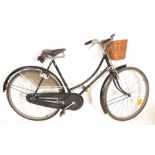 A vintage retro 1970's Raleigh road bike having a black tubular frame with wicker basket to the