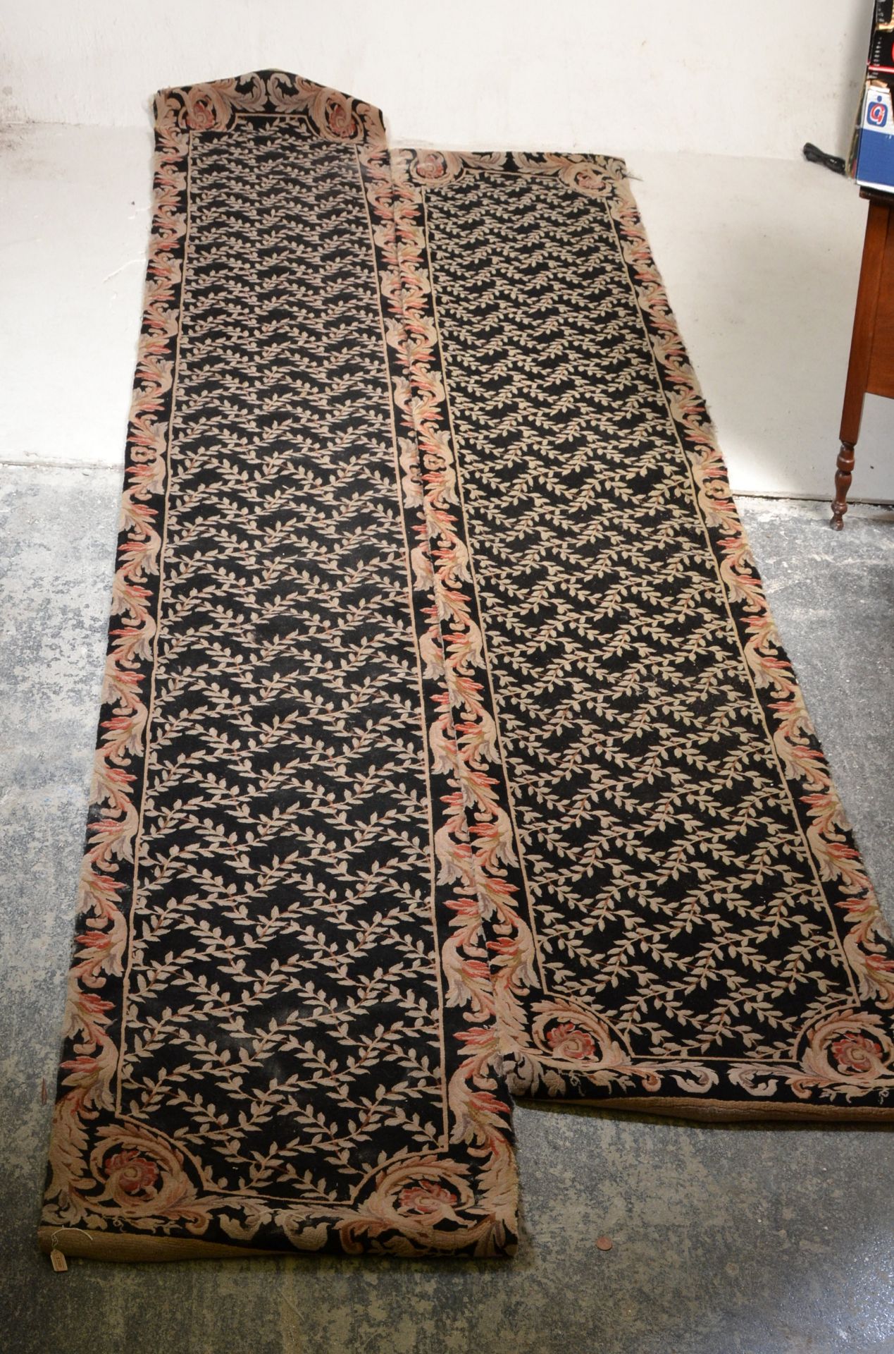 A matching pair of vintage 20th Century floor rug runners having black ground with cream floral