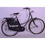 A vintage retro 20th Century fixed gear bike having a black tubular frame, a pannier rack to the