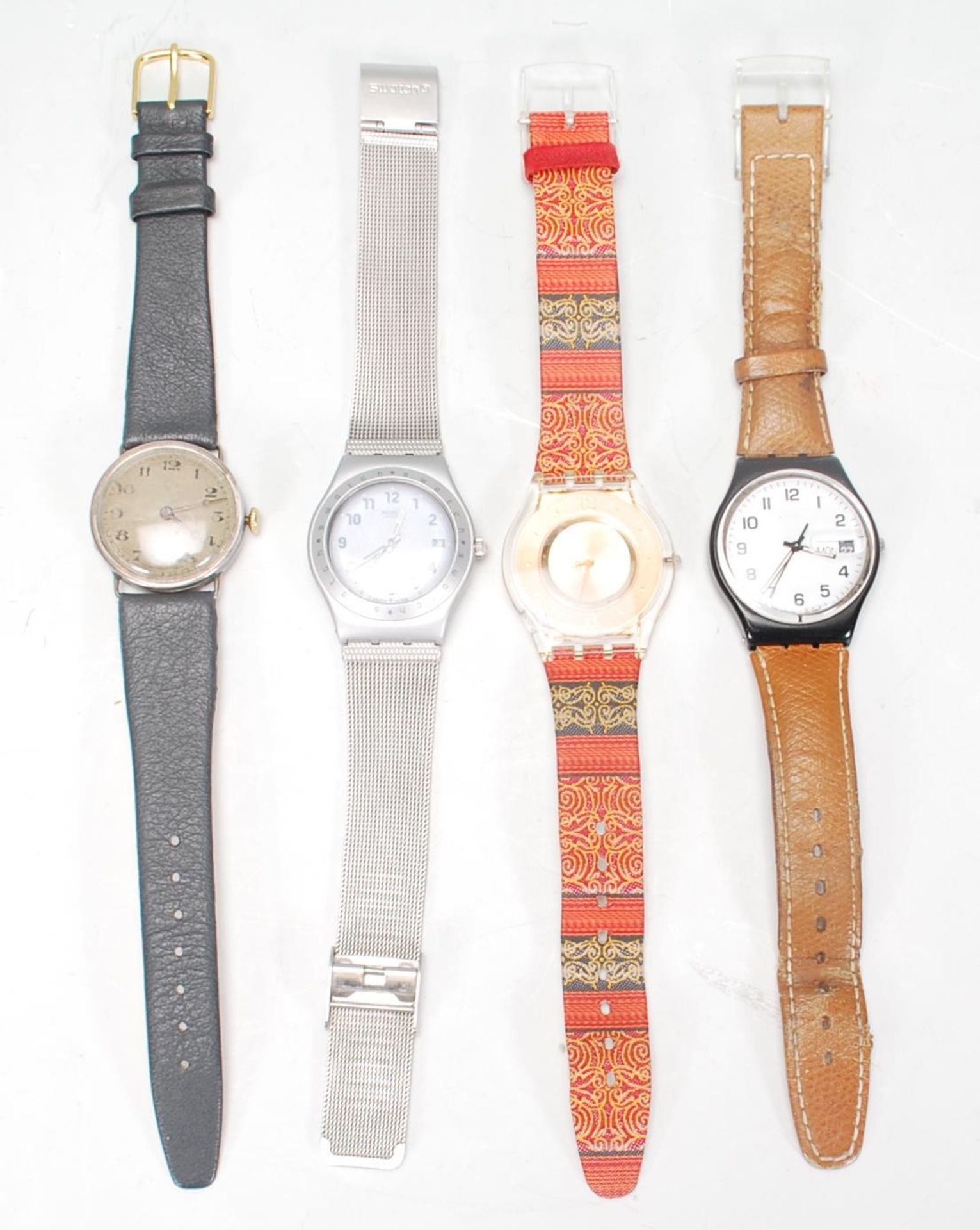 A group of three Swatch watches to include a silver tone bracelet watch, a brown leather strapped