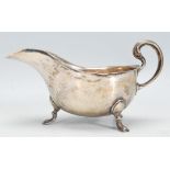 An early 20th Century silver hallmarked sauce / gravy boat raised on hoof feet with flared rim and
