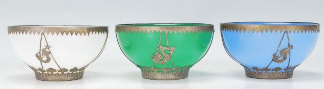 A group of three early 20th Century Chinese brass mounted multi coloured glass bowls having white