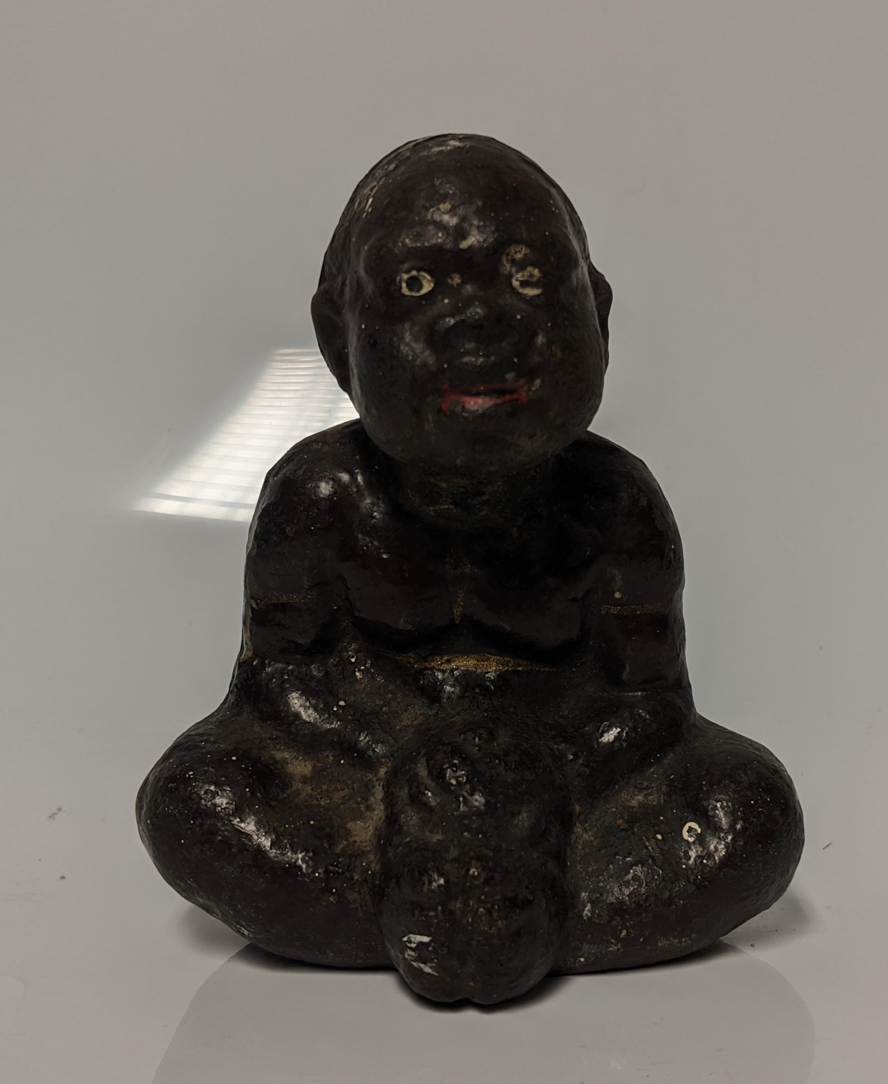 An early 20th century cast iron Black Americana paperweight / figurine of a seated male figure being