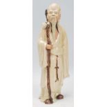 A Chinese Shiwan earthenware standing figure ornament of an Immortal, Shou, depicted holding a