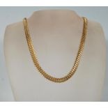 A contemporary gold plated flat fancy link chain necklace having large woven links with a tongue