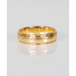 An 18ct gold wedding band ring having engraved twist decoration with faceted borders. Marked 750