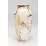 A Japanese ceramic vase of tapering cylindrical form with a flared rim being hand painted with