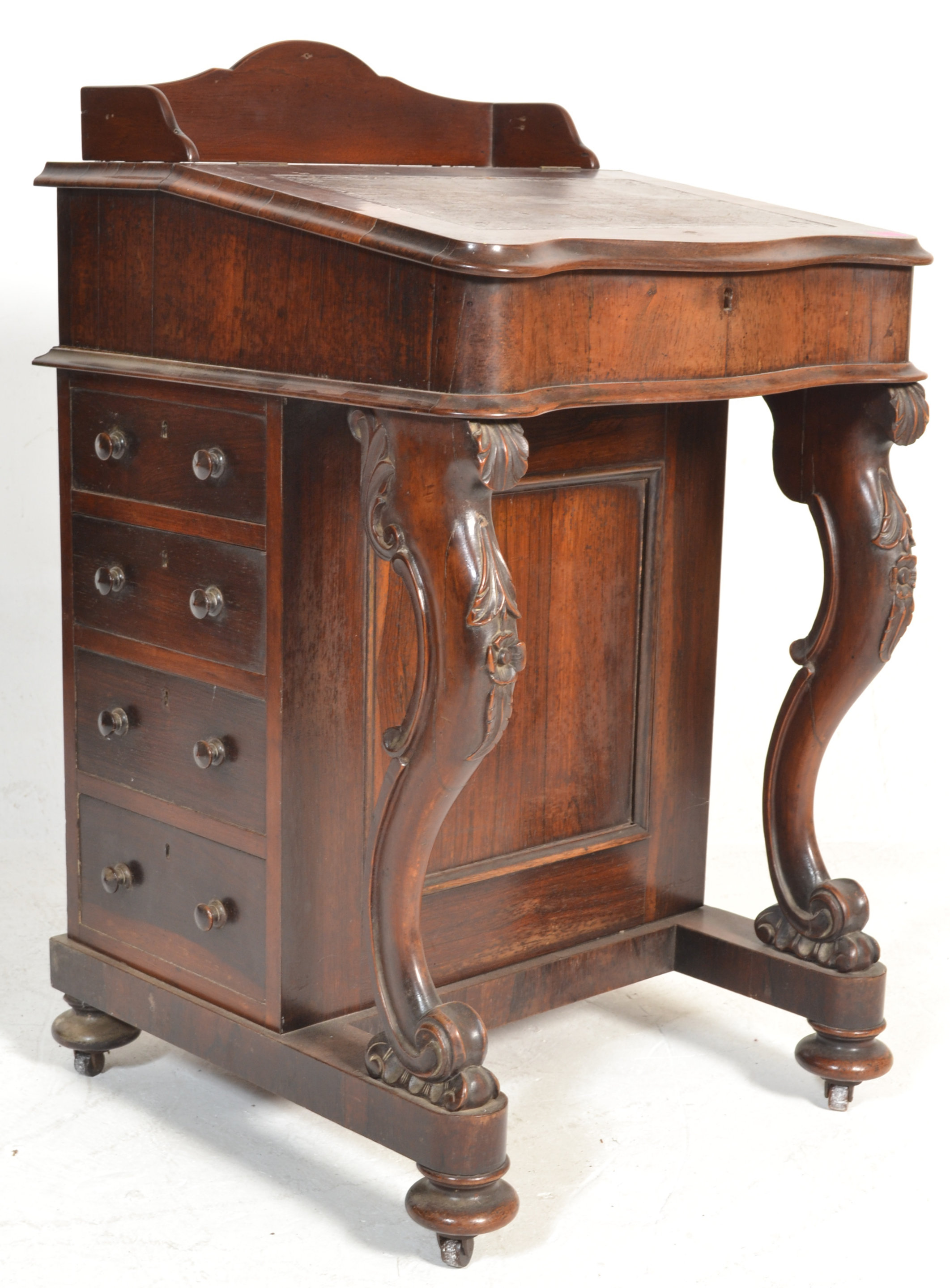A Victorian 19th century rosewood davenport desk being raised on scroll supports with carved