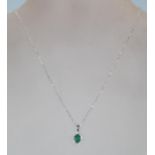 A ladies stamped 18CT white gold chain necklace. An oval emerald is set centrally amidst a halo of