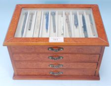 A collection of 20th Century propelling pencils set within a walnut display case with sectional