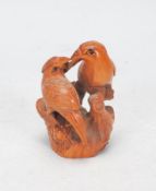 A Japanese carved wood Netsuke toggle in the form of two parrots on wooden perches touching beaks,