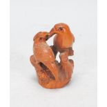 A Japanese carved wood Netsuke toggle in the form of two parrots on wooden perches touching beaks,