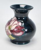 A Moorcroft vase of squat bulbous form. Tubelined decorated in the purple and white Magnolia