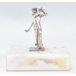 A silver hallmarked desktop figurine in the form of a golfer in mid swing being raised on a square