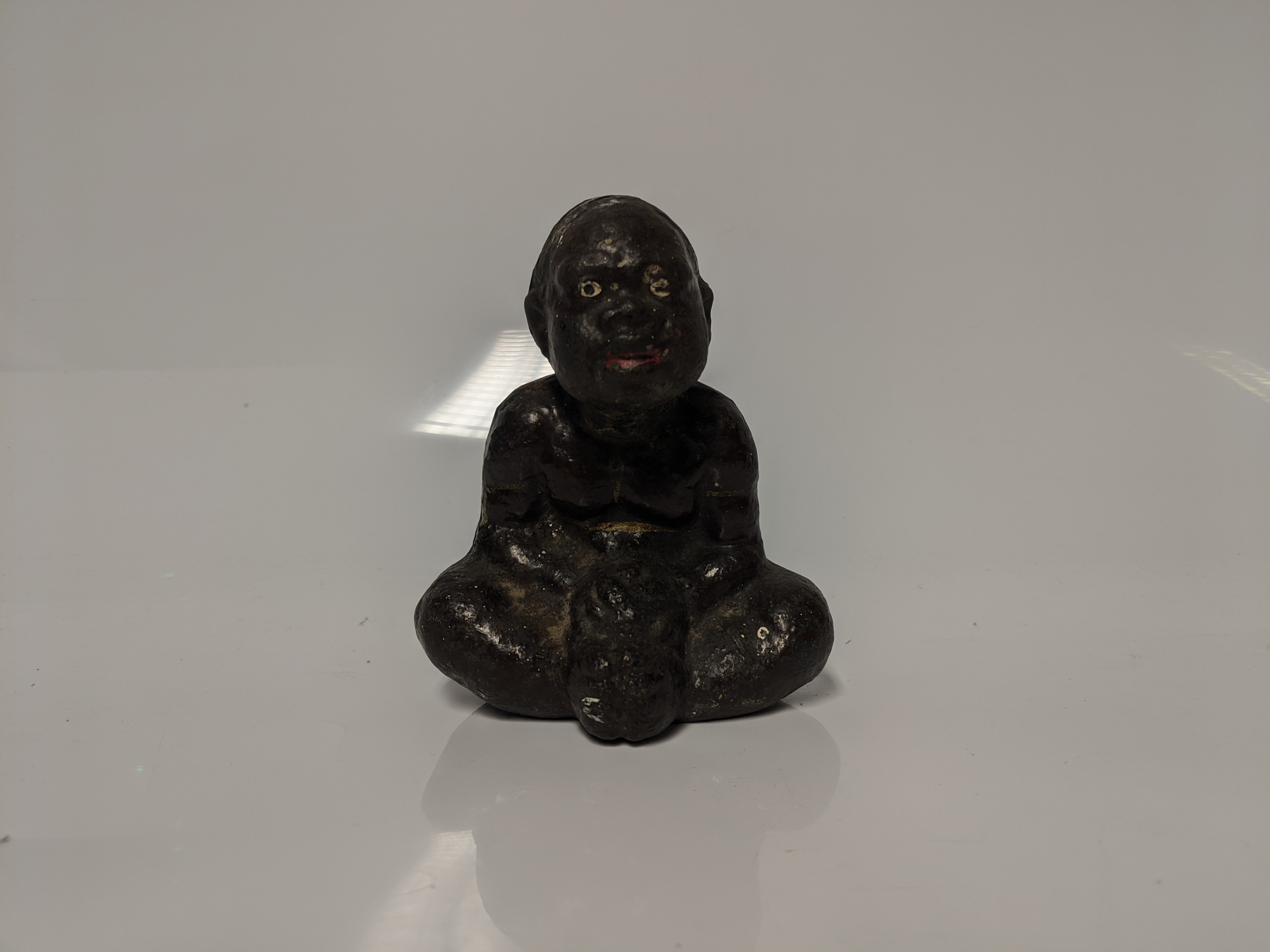 An early 20th century cast iron Black Americana paperweight / figurine of a seated male figure being - Image 2 of 5