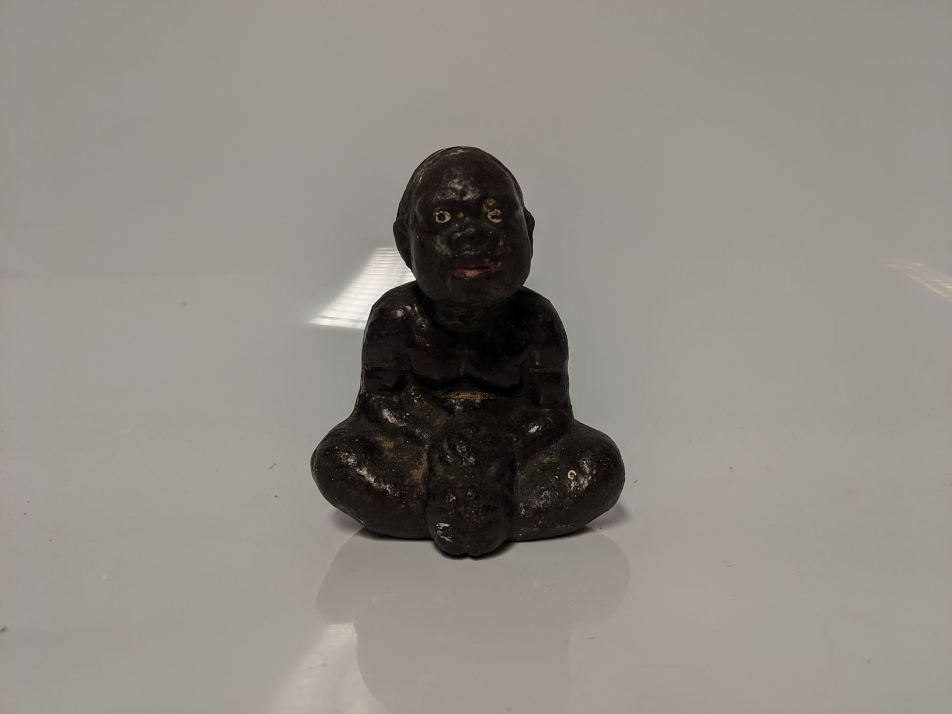 An early 20th century cast iron Black Americana paperweight / figurine of a seated male figure being - Bild 2 aus 5