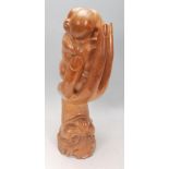 An unusual hardwood carved sculpture depicting face with hand coming out of the mouth and holding